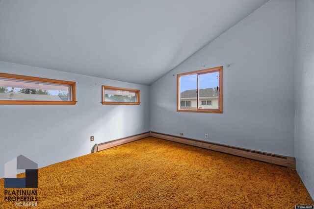 unfurnished room featuring vaulted ceiling, plenty of natural light, and baseboard heating