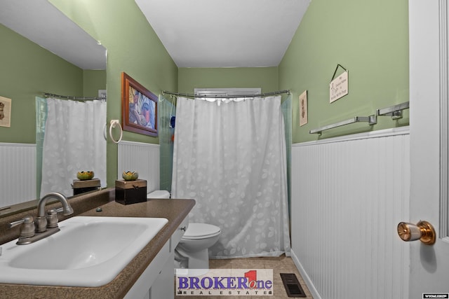 bathroom featuring wainscoting, toilet, vanity, curtained shower, and tile patterned floors