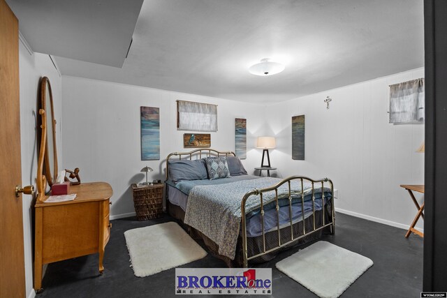 bedroom with baseboards and finished concrete flooring