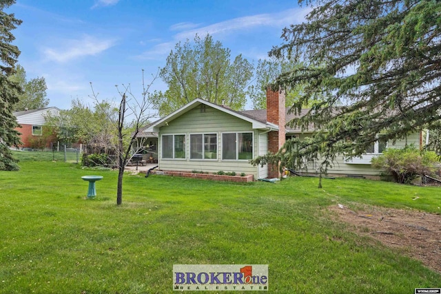 rear view of property featuring a chimney and a yard