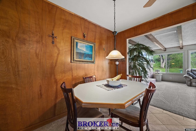 carpeted dining room featuring tile patterned flooring, wood walls, and beam ceiling
