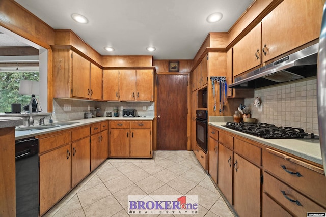 kitchen featuring black appliances, a sink, under cabinet range hood, tasteful backsplash, and light countertops
