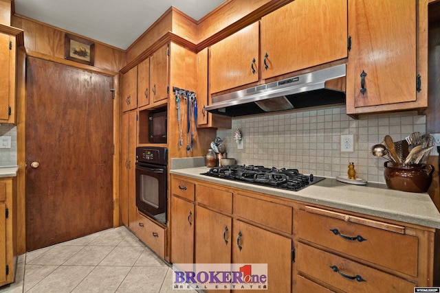 kitchen featuring under cabinet range hood, black appliances, tasteful backsplash, light countertops, and light tile patterned floors
