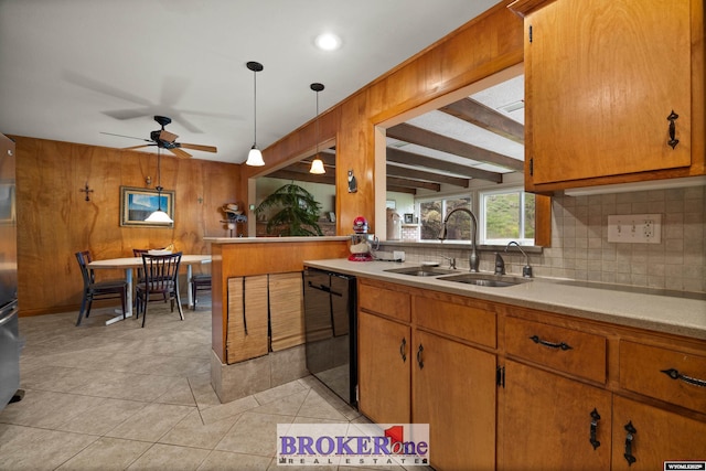 kitchen featuring dishwasher, a sink, tasteful backsplash, light countertops, and wooden walls