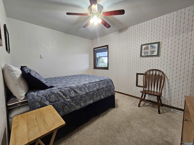 1008 N Rd 11, Worland, WY 82401 - carpeted bedroom featuring wallpapered walls, baseboards, a textured ceiling, and a ceiling fan