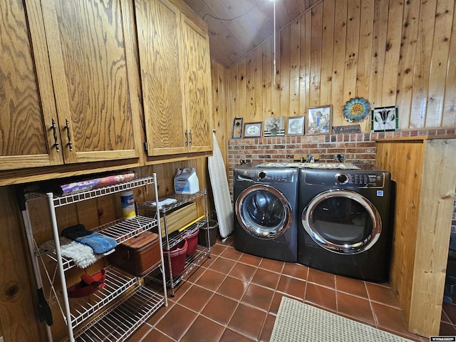 1008 N Rd 11, Worland, WY 82401 - laundry area with cabinet space, washing machine and dryer, dark tile patterned floors, and wood walls