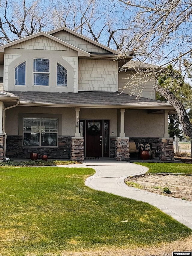 101 Pebble Ln, Torrington, WY 82240 - view of front of house with stone siding, stucco siding, a front yard, and covered porch