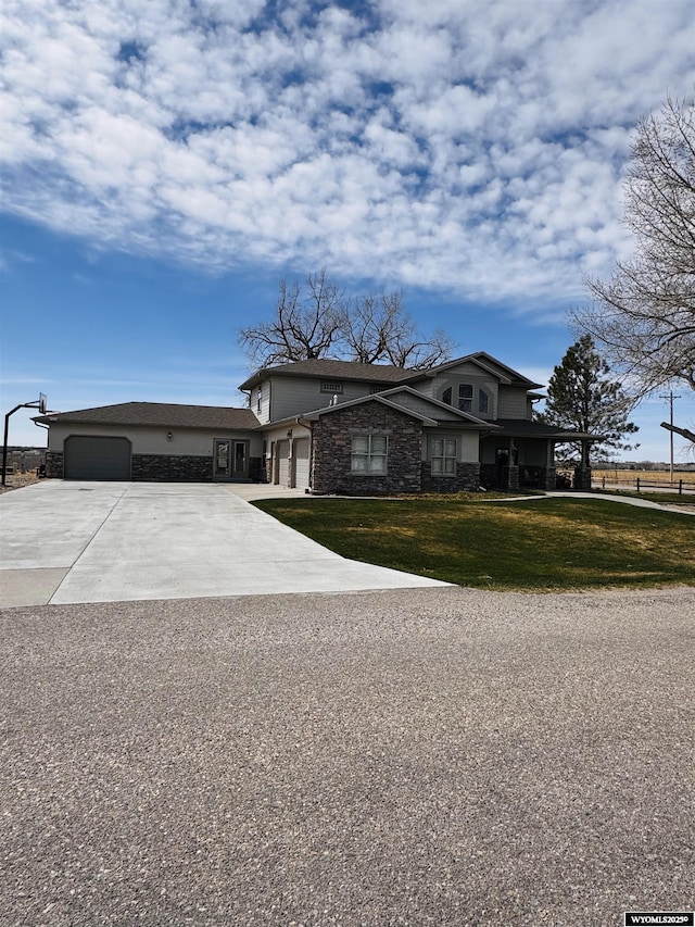 101 Pebble Ln, Torrington, WY 82240 - view of front of house with stone siding, concrete driveway, a front lawn, and an attached garage