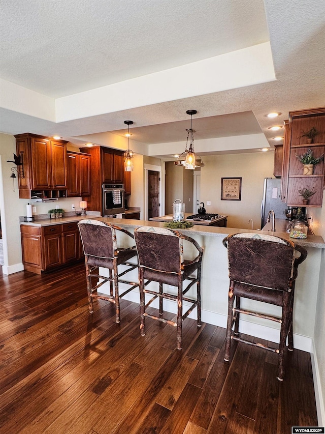 101 Pebble Ln, Torrington, WY 82240 - kitchen featuring a kitchen bar, dark wood-style floors, a raised ceiling, open shelves, and pendant lighting