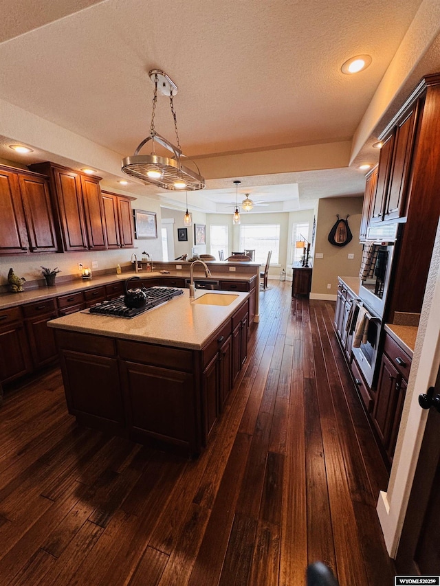 101 Pebble Ln, Torrington, WY 82240 - kitchen with a sink, gas stovetop, dark wood finished floors, open floor plan, and decorative light fixtures