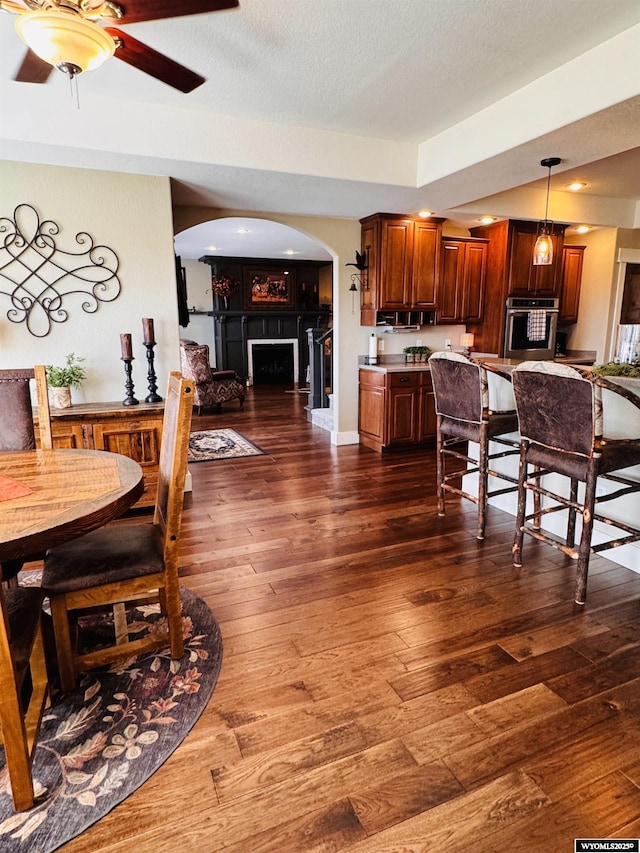 101 Pebble Ln, Torrington, WY 82240 - dining area featuring arched walkways, a fireplace, dark wood-type flooring, a ceiling fan, and a textured ceiling