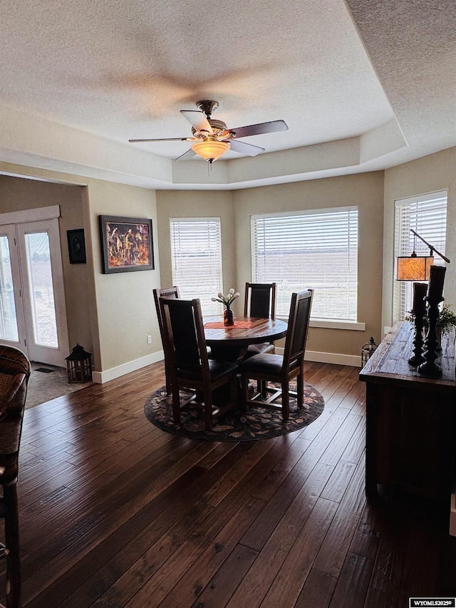 101 Pebble Ln, Torrington, WY 82240 - dining space featuring a textured ceiling, baseboards, dark wood-style flooring, ceiling fan, and a raised ceiling