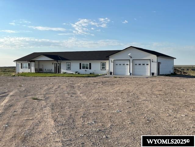 ranch-style home with an attached garage and dirt driveway