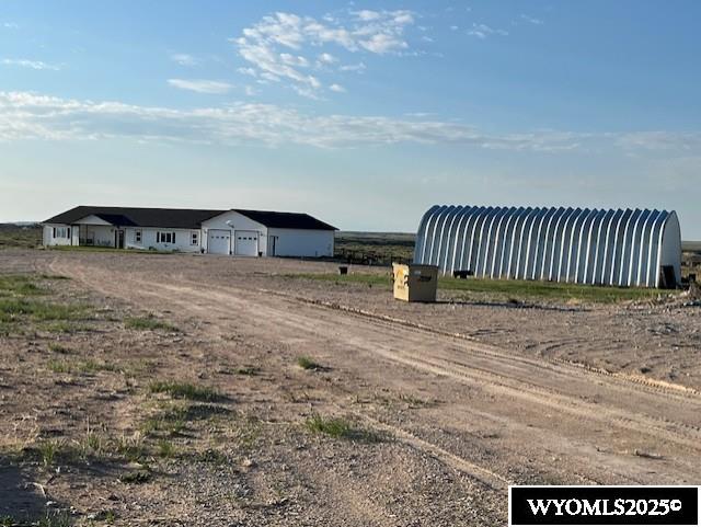 view of yard with driveway, an attached garage, an outbuilding, and a pole building