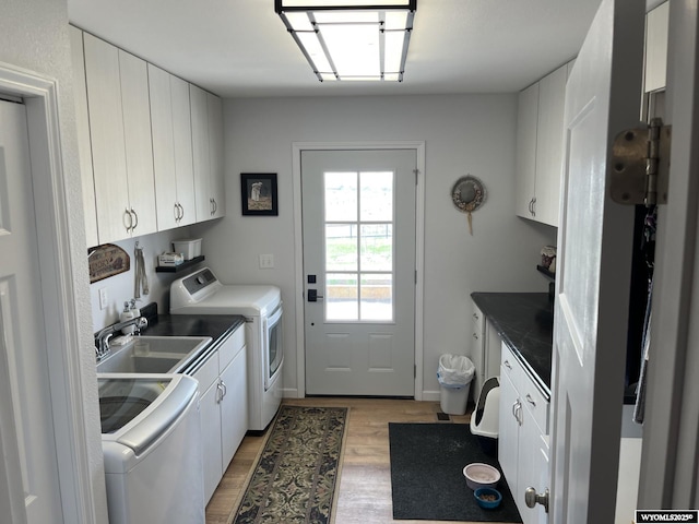 washroom featuring cabinet space, separate washer and dryer, and light wood-style flooring