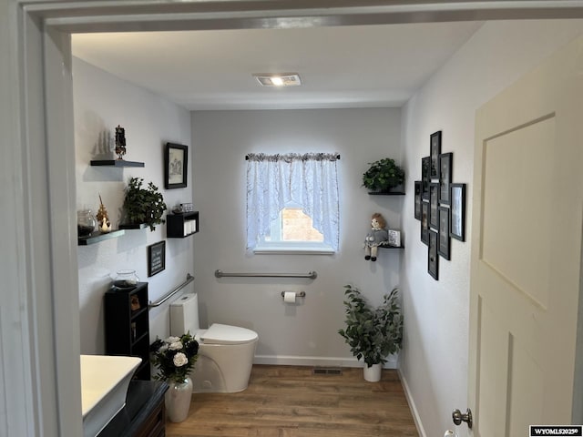 bathroom with toilet, wood finished floors, vanity, and baseboards
