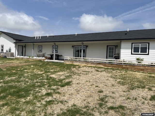 rear view of house featuring a lawn and central AC unit