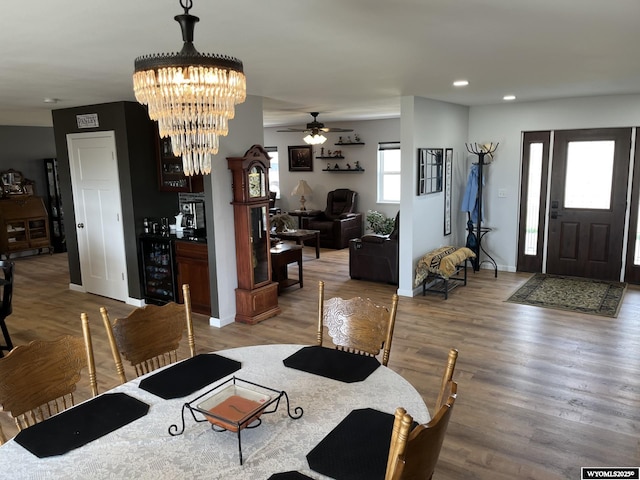 dining space with wood finished floors, recessed lighting, ceiling fan, baseboards, and a chandelier