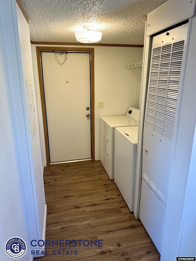 laundry area featuring washer and dryer, a textured ceiling, a heating unit, and wood finished floors