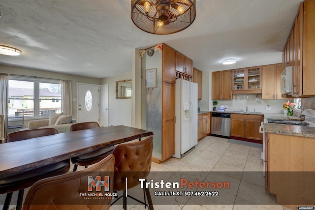 2819 E 6th St, Casper, WY 82609 - kitchen with white appliances, brown cabinets, a sink, glass insert cabinets, and light tile patterned floors