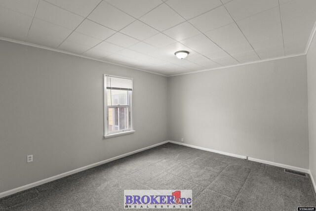 empty room featuring crown molding, carpet floors, and baseboards