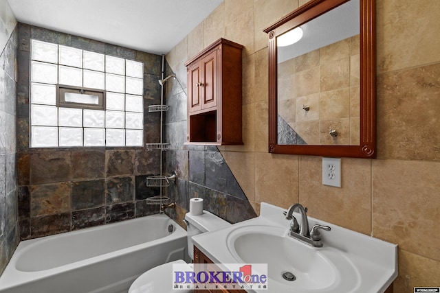 full bath with tile walls, shower / tub combination, toilet, and vanity