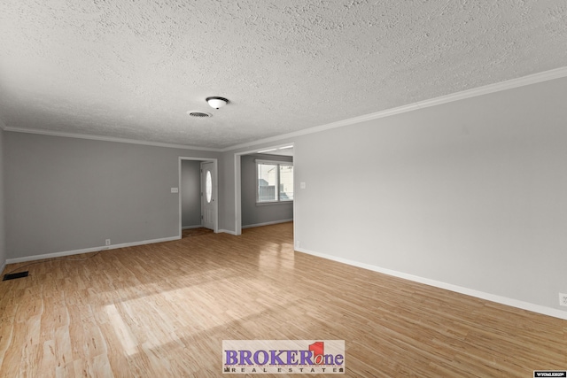 empty room with light wood-style flooring, a textured ceiling, ornamental molding, and baseboards