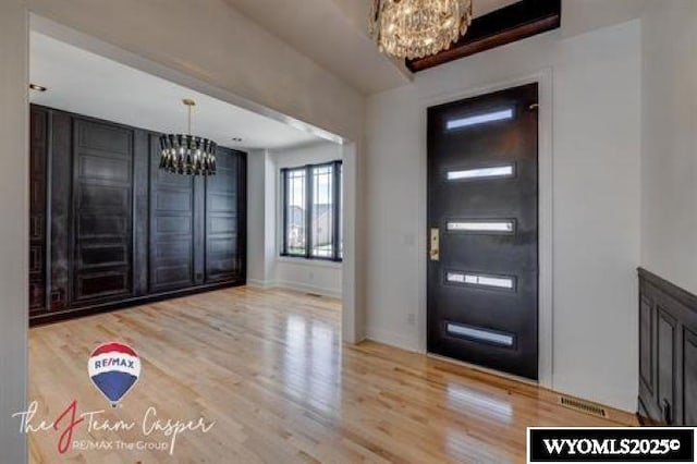 foyer entrance featuring a chandelier, wood finished floors, and baseboards