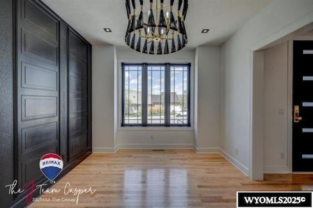 unfurnished dining area with a chandelier, baseboards, and light wood-type flooring