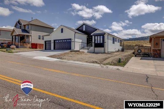 view of front of house featuring an attached garage, concrete driveway, and fence