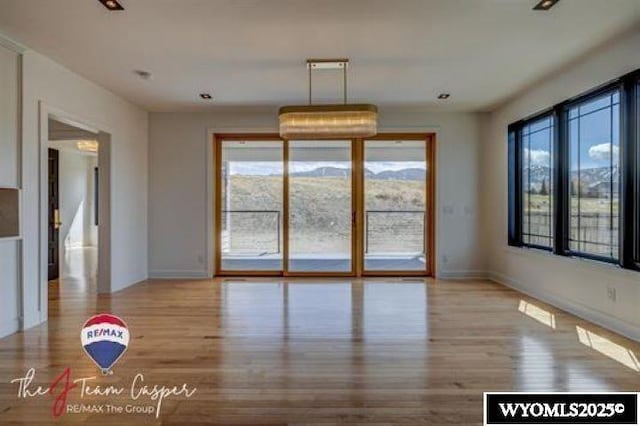 unfurnished dining area with wood finished floors, plenty of natural light, and baseboards