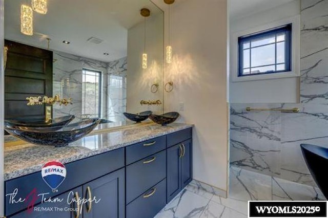 bathroom with plenty of natural light, marble finish flooring, and double vanity