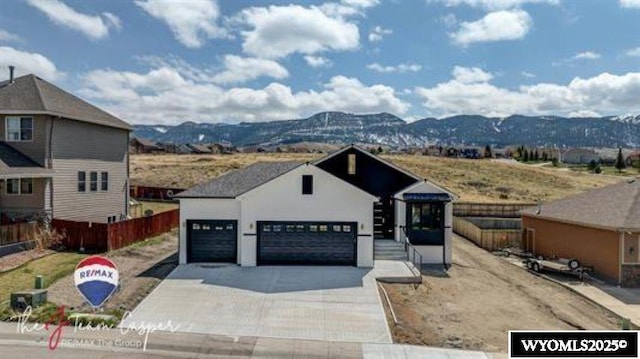 view of front of house featuring a mountain view, fence, concrete driveway, and stucco siding
