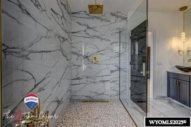bathroom with a marble finish shower, vanity, and marble finish flooring