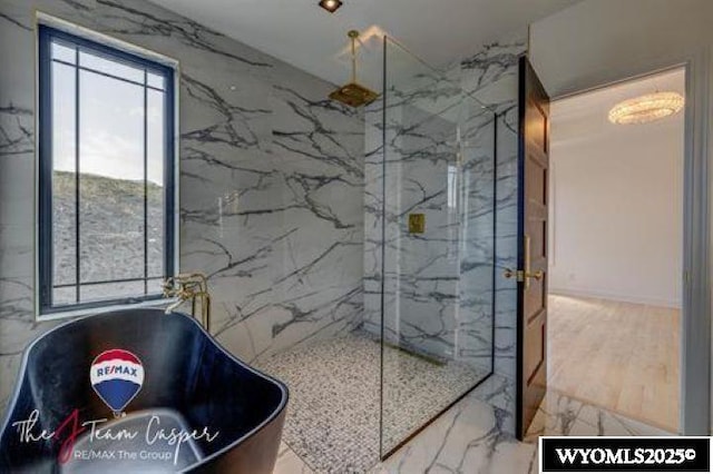 full bathroom with a marble finish shower and a freestanding bath