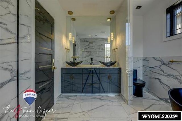 full bath featuring marble tiled flooring, vanity, and toilet