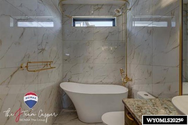 bathroom featuring vanity, a freestanding tub, a marble finish shower, tile walls, and marble finish floors