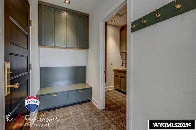 mudroom with dark tile patterned floors and baseboards