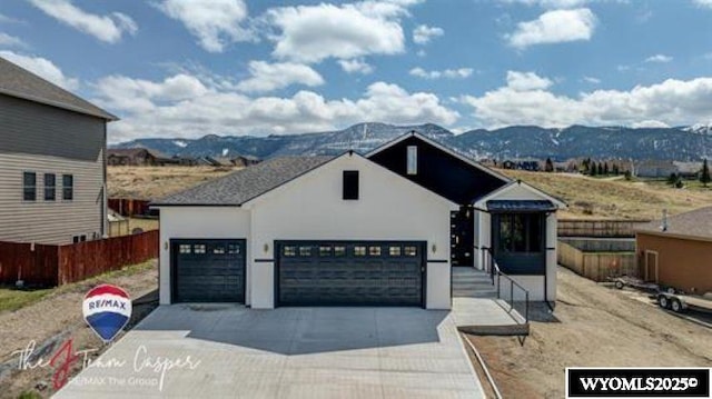 view of front of home featuring a garage, driveway, a mountain view, and fence