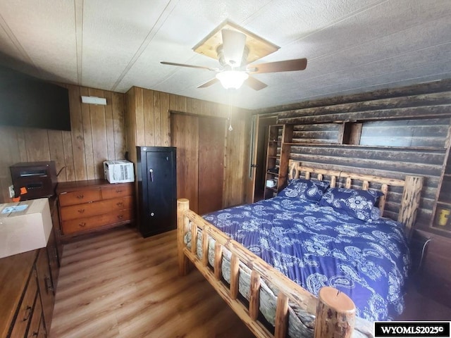 bedroom with wooden walls, wood finished floors, and ceiling fan