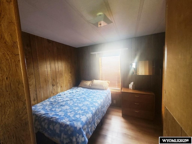 bedroom featuring wood finished floors and wooden walls