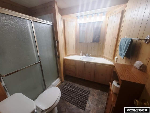 bathroom featuring toilet, a shower stall, wood walls, and vanity