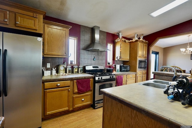 33 Oxbow Rd, Buffalo, WY 82834 - kitchen featuring stainless steel appliances, wall chimney range hood, tasteful backsplash, a sink, and light wood-style flooring