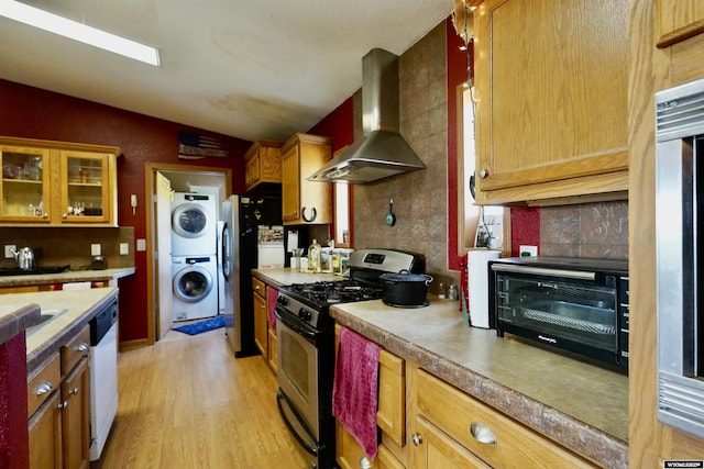 33 Oxbow Rd, Buffalo, WY 82834 - kitchen with appliances with stainless steel finishes, stacked washing machine and dryer, wall chimney range hood, vaulted ceiling, and light wood-style flooring