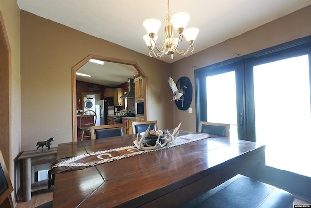 33 Oxbow Rd, Buffalo, WY 82834 - dining space with a chandelier, stacked washer and clothes dryer, arched walkways, dark wood-type flooring, and french doors