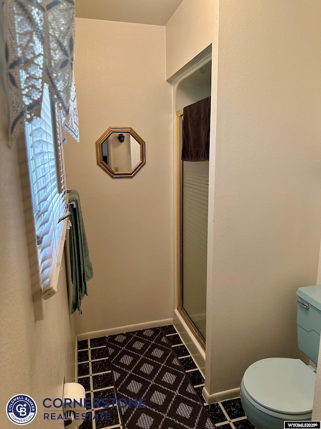 full bath with a stall shower, toilet, and baseboards