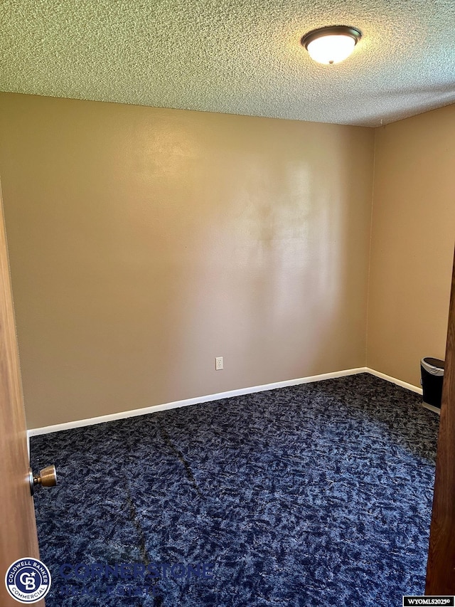 carpeted spare room with a textured ceiling and baseboards