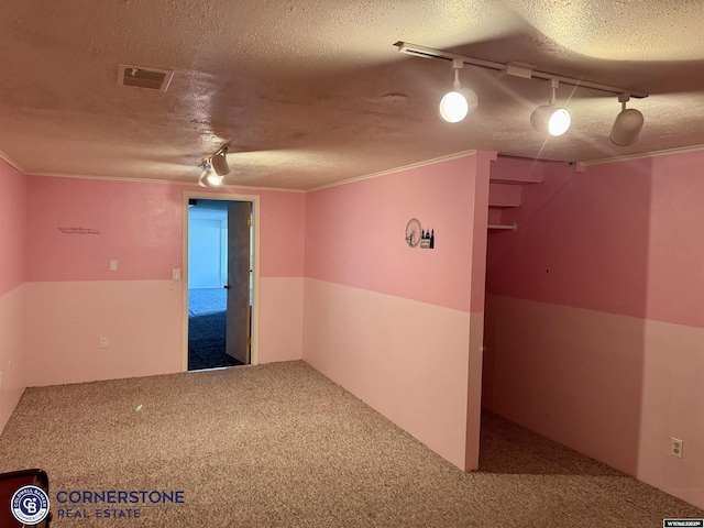 carpeted empty room featuring rail lighting, a textured ceiling, and crown molding