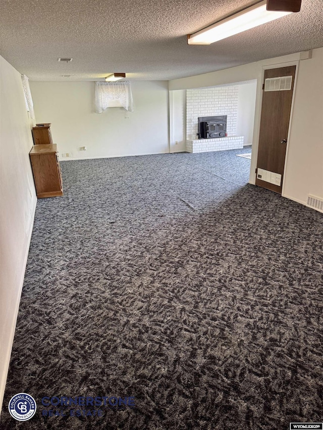 unfurnished living room with a brick fireplace, carpet, and a textured ceiling