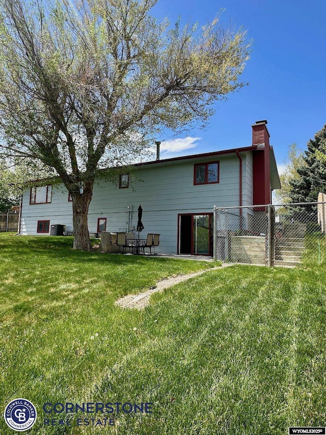 rear view of property with a chimney and cooling unit